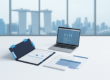 Flat-lay of laptop, documents, and folder in corporate workspace with Singapore skyline reflection.